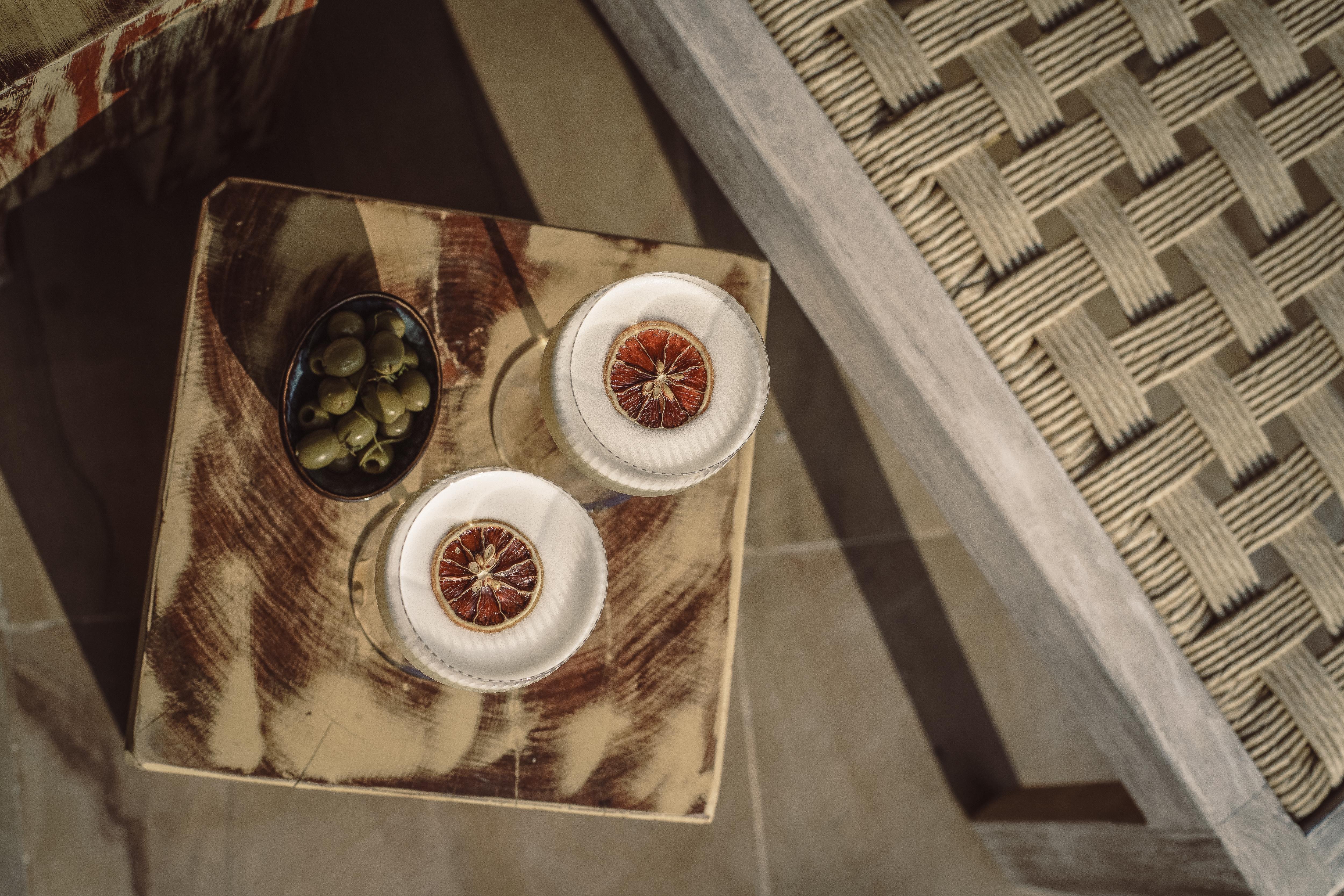 Cocktails with dried blood orange served poolside at Namia — sundowner ritual
