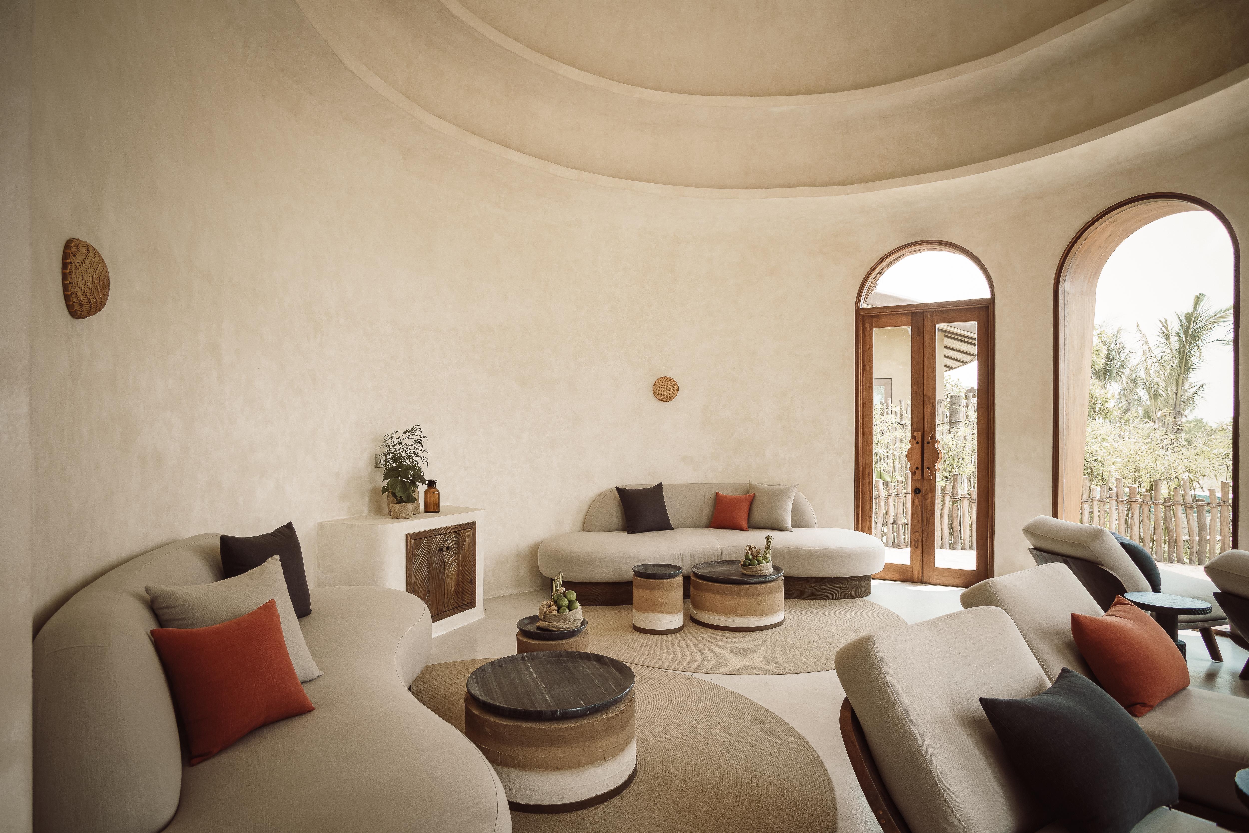 A warm bedroom interior with timber ceiling, linen, and natural materials, opening onto a private pool
